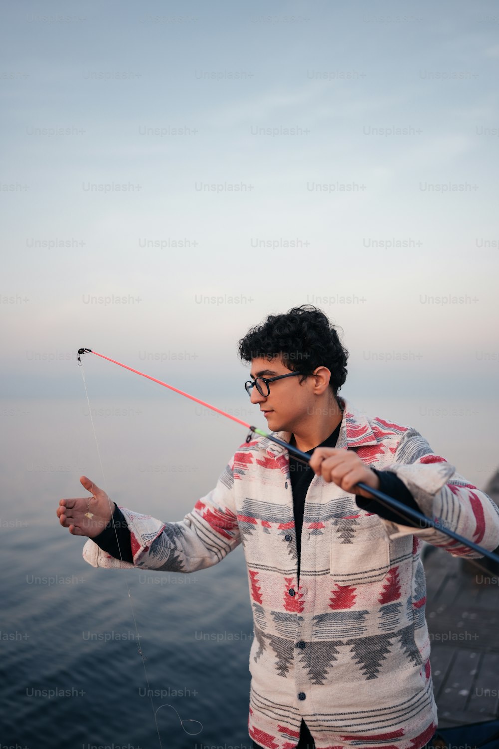 a young man holding a fishing rod on a boat