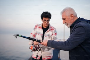 Un hombre sosteniendo una caña de pescar junto a otro hombre