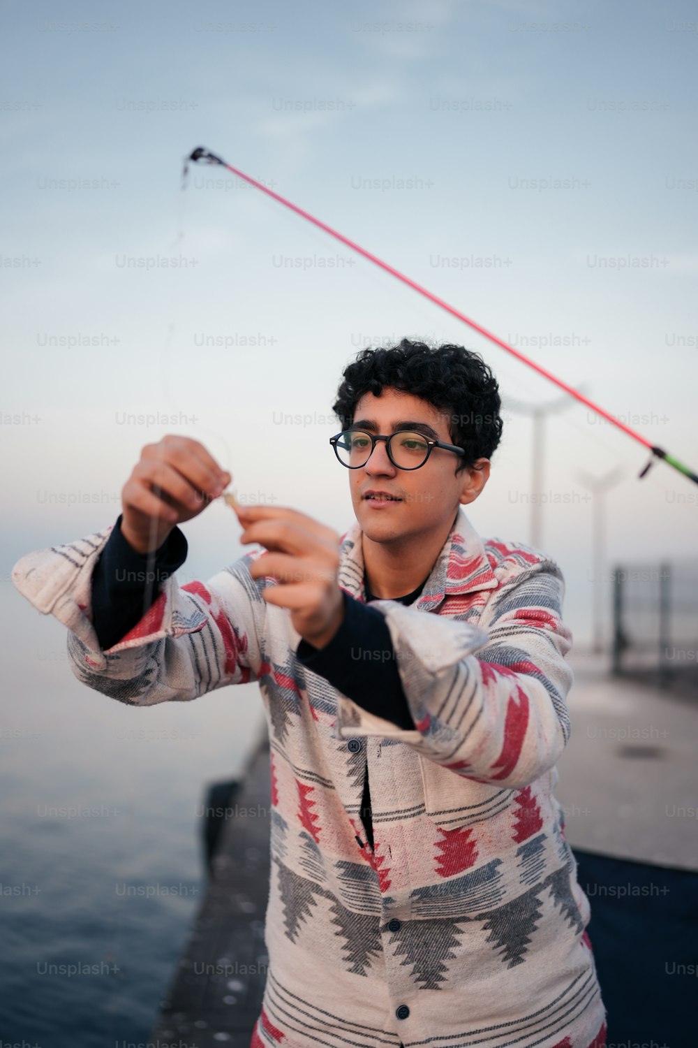 a man holding a fishing rod while standing next to a body of water