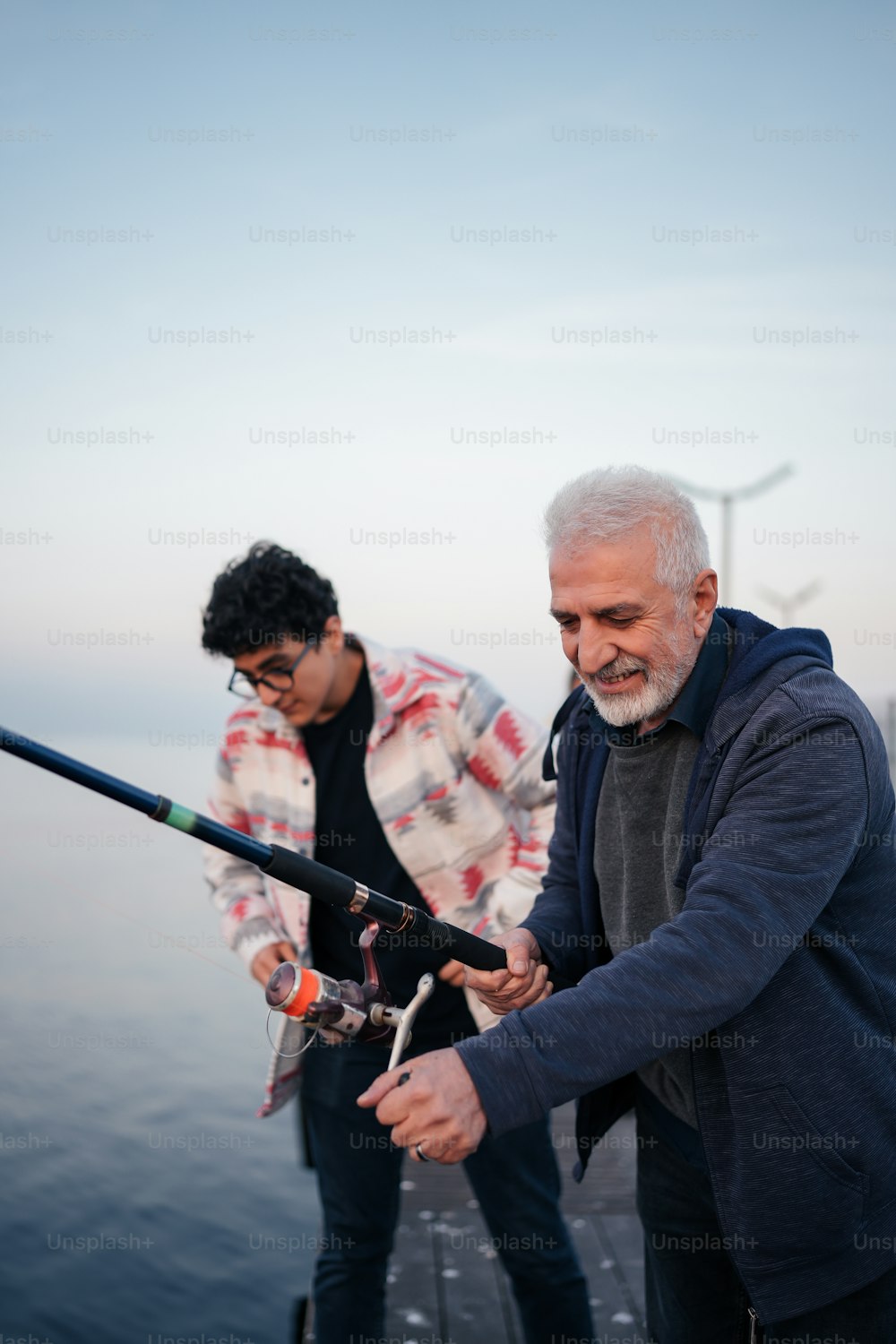Un hombre sosteniendo una caña de pescar junto a otro hombre