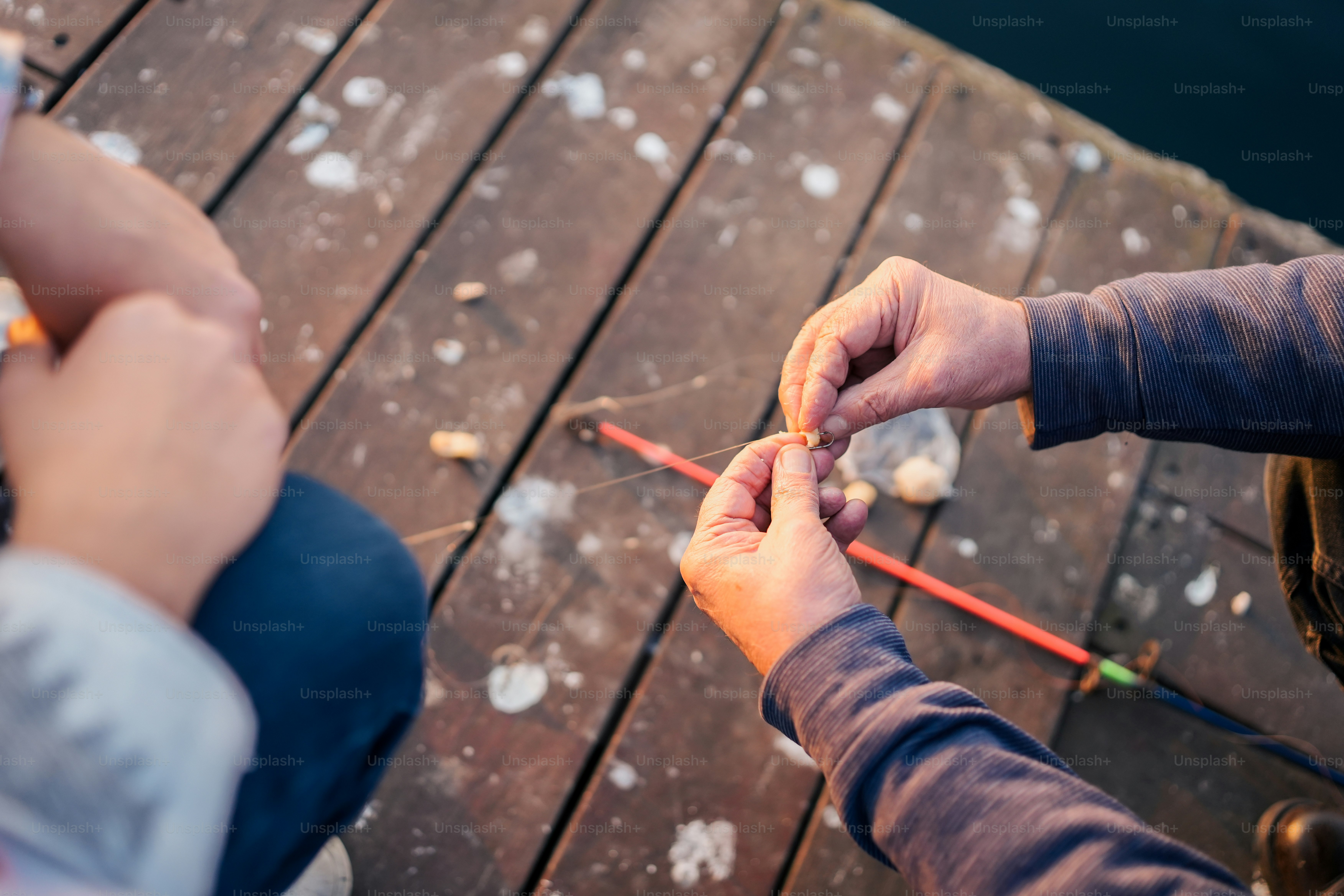 a couple of people sitting on top of a wooden dock