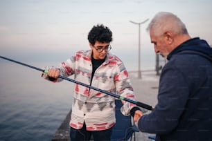 a man holding a fishing rod next to another man