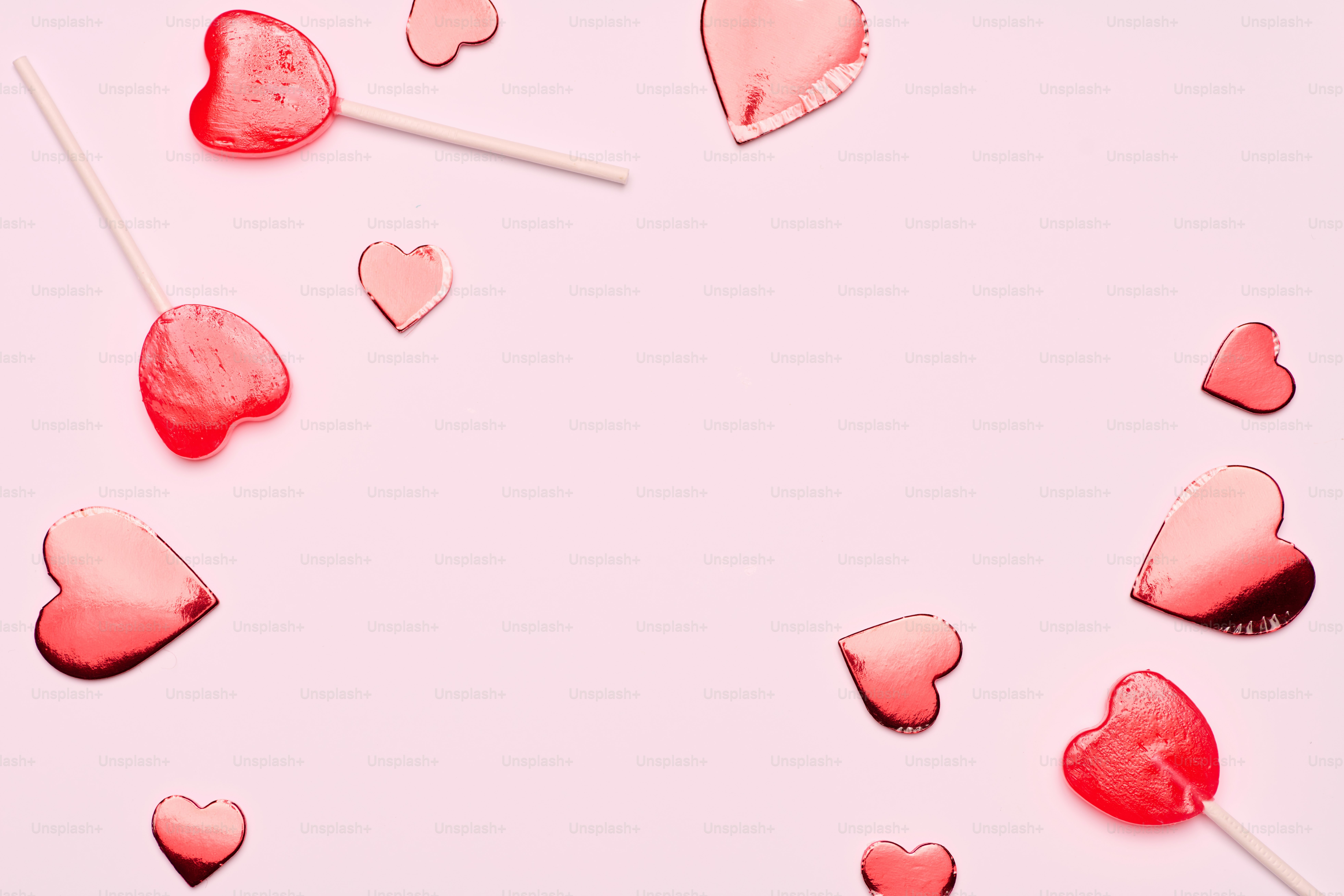 un gruppo di lecca-lecca a forma di cuore su uno sfondo rosa