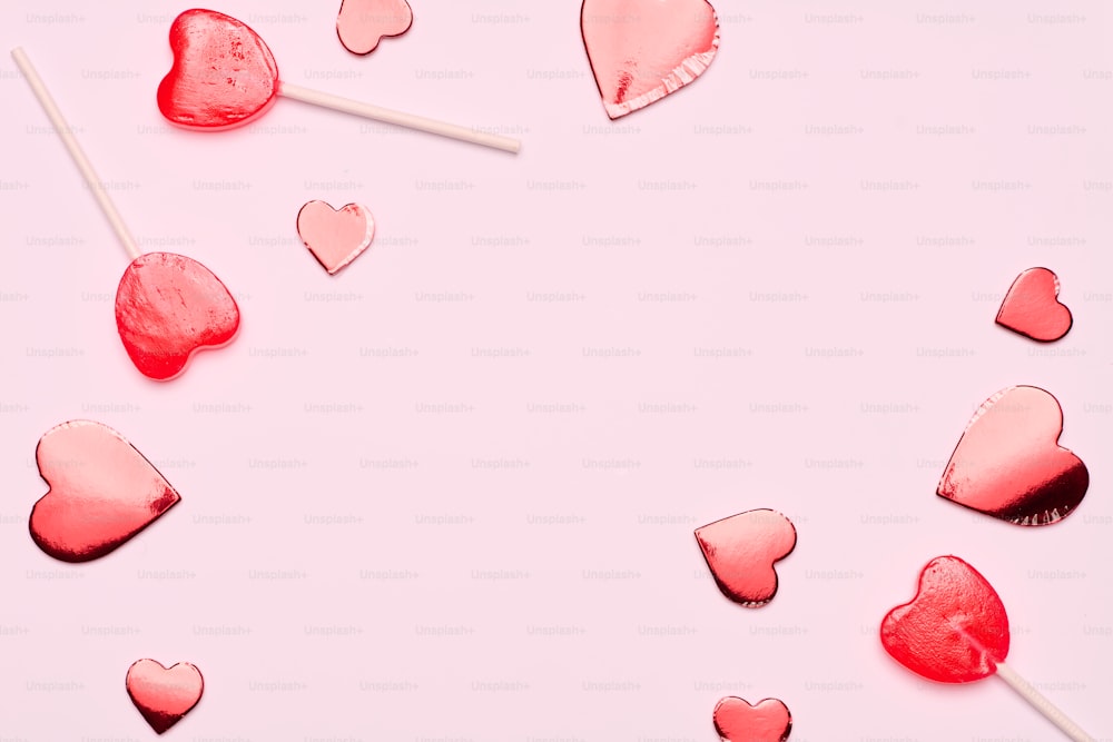 um grupo de pirulitos em forma de coração em um fundo rosa