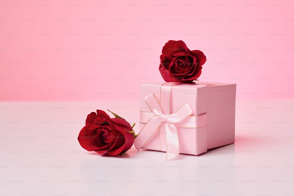 白い箱の上に座っている2本の赤いバラ