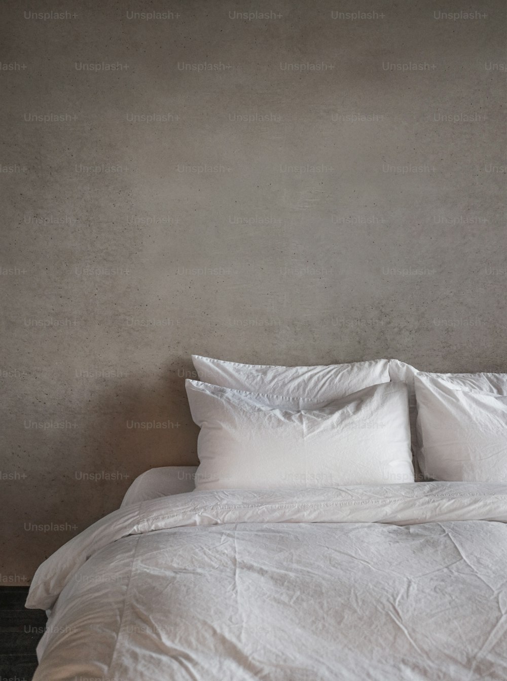 una cama con edredón blanco y almohadas