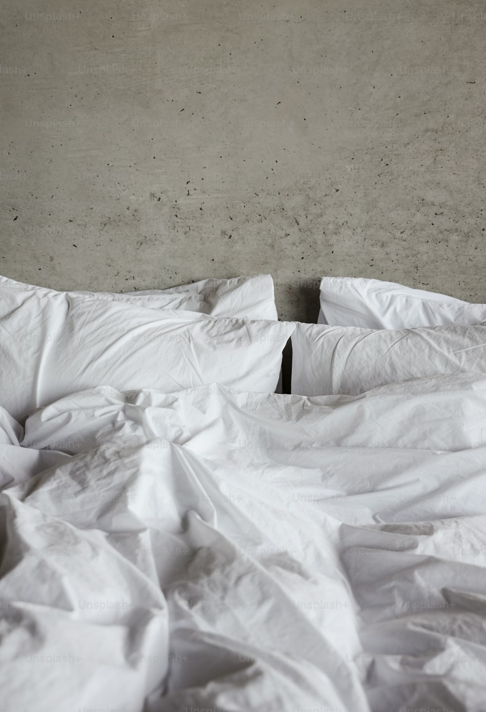 uma cama desfeita com lençóis brancos e travesseiros