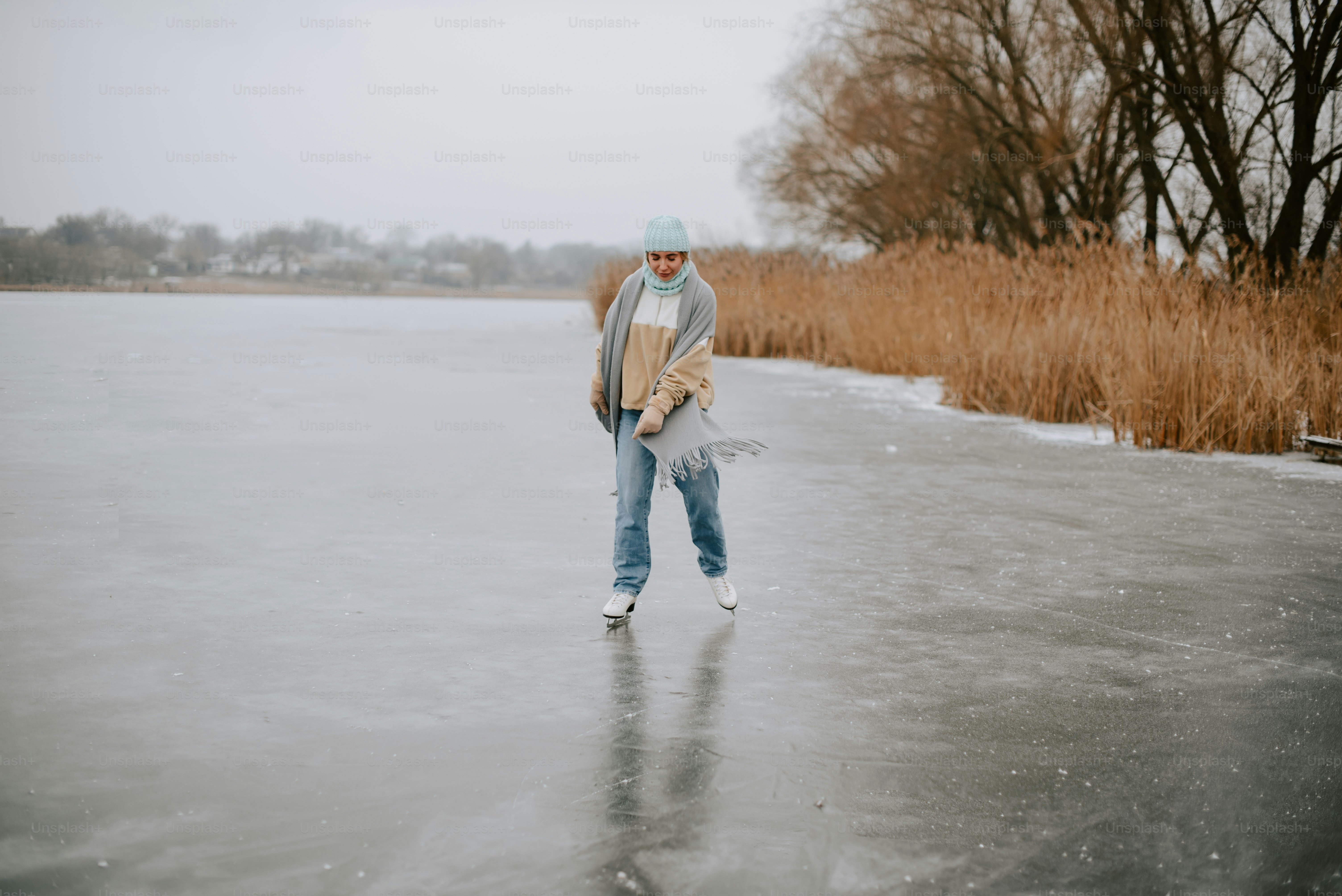 a man walking across a frozen lake holding a skateboard