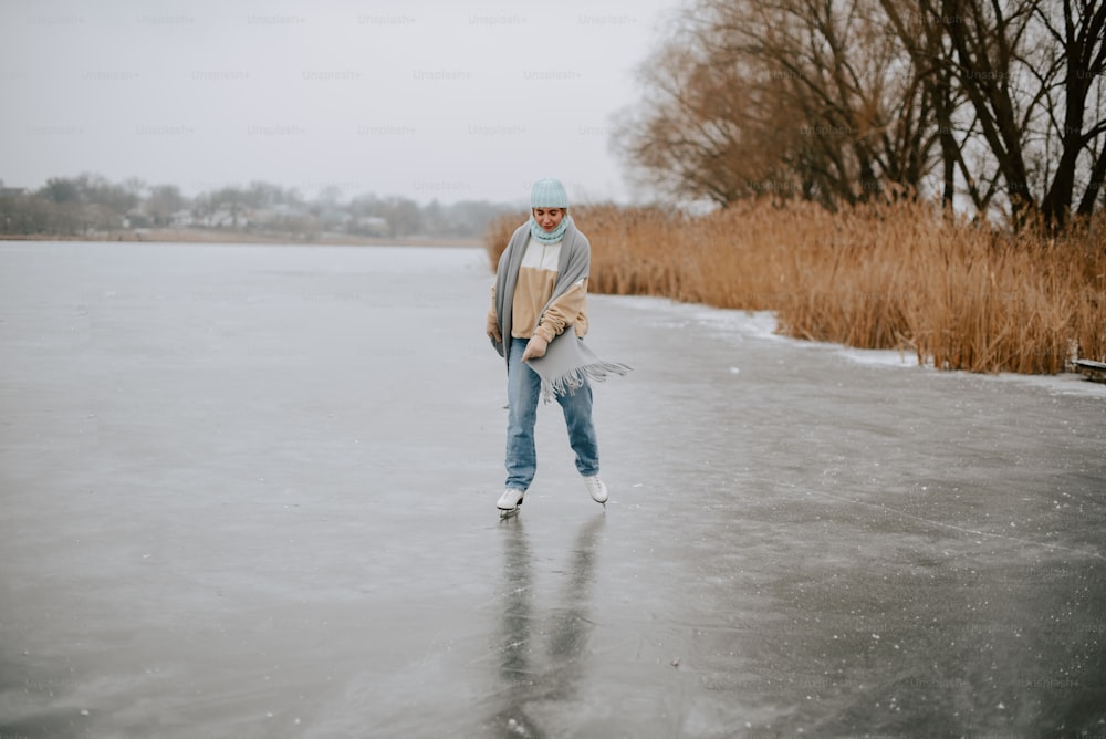 a man walking across a frozen lake holding a skateboard