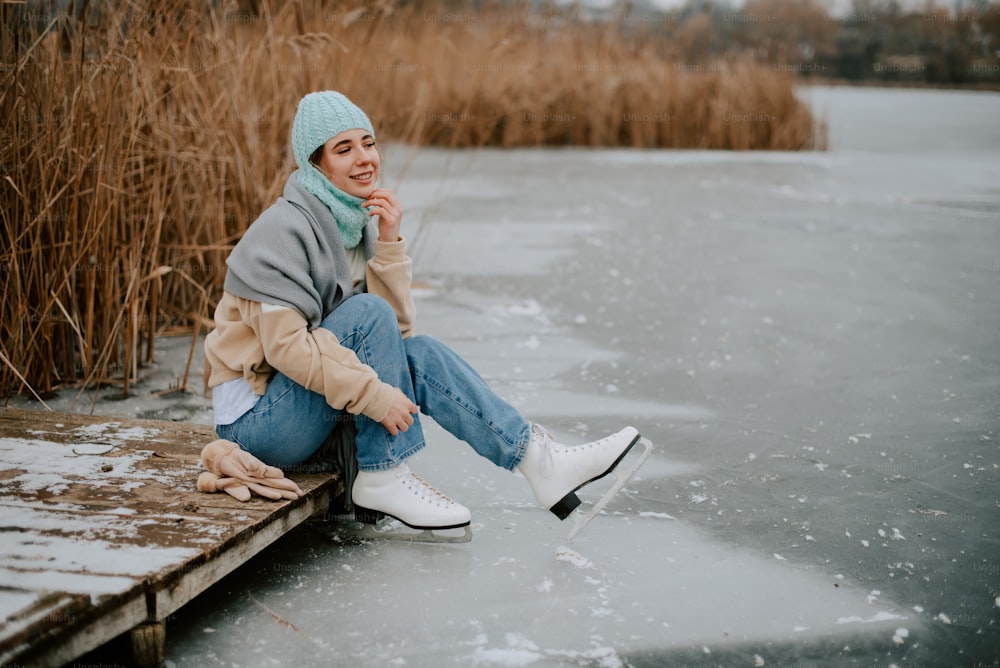 a woman sitting on a dock in the snow
