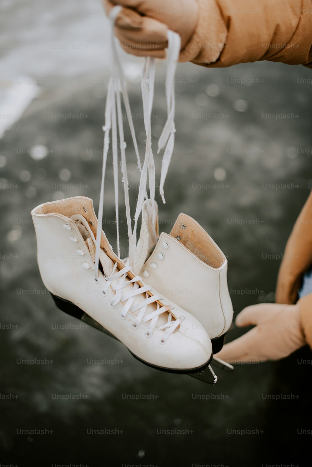 Un par de patines de hielo blanco sostenidos por alguien
