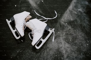 une paire de patins à glace blancs assis sur une surface noire