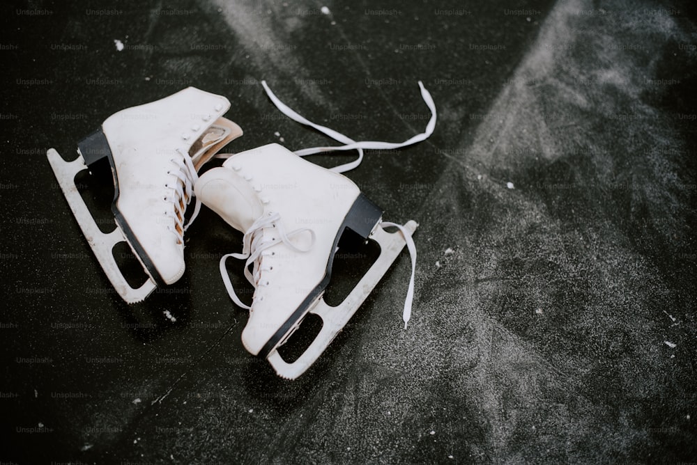 Un par de patines de hielo blanco sentados encima de una superficie negra
