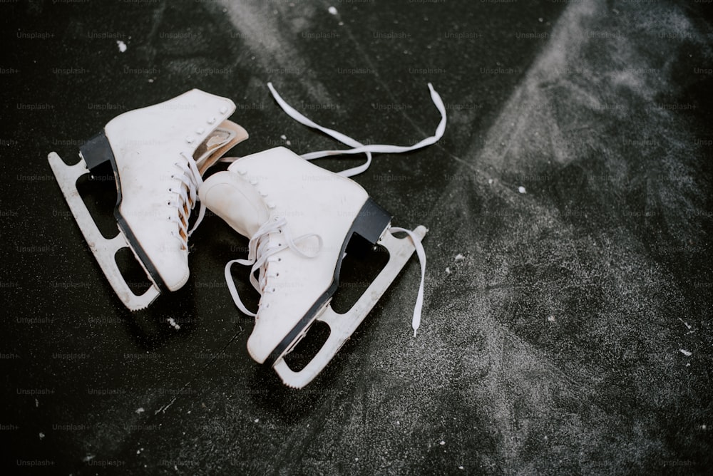 a pair of white ice skates sitting on top of a black surface