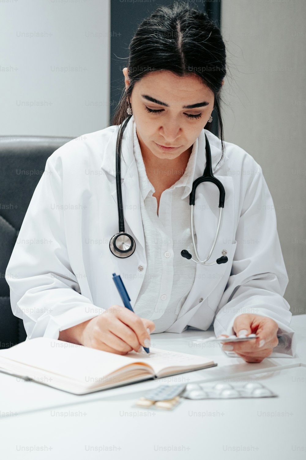 a woman in a white lab coat writing on a notebook