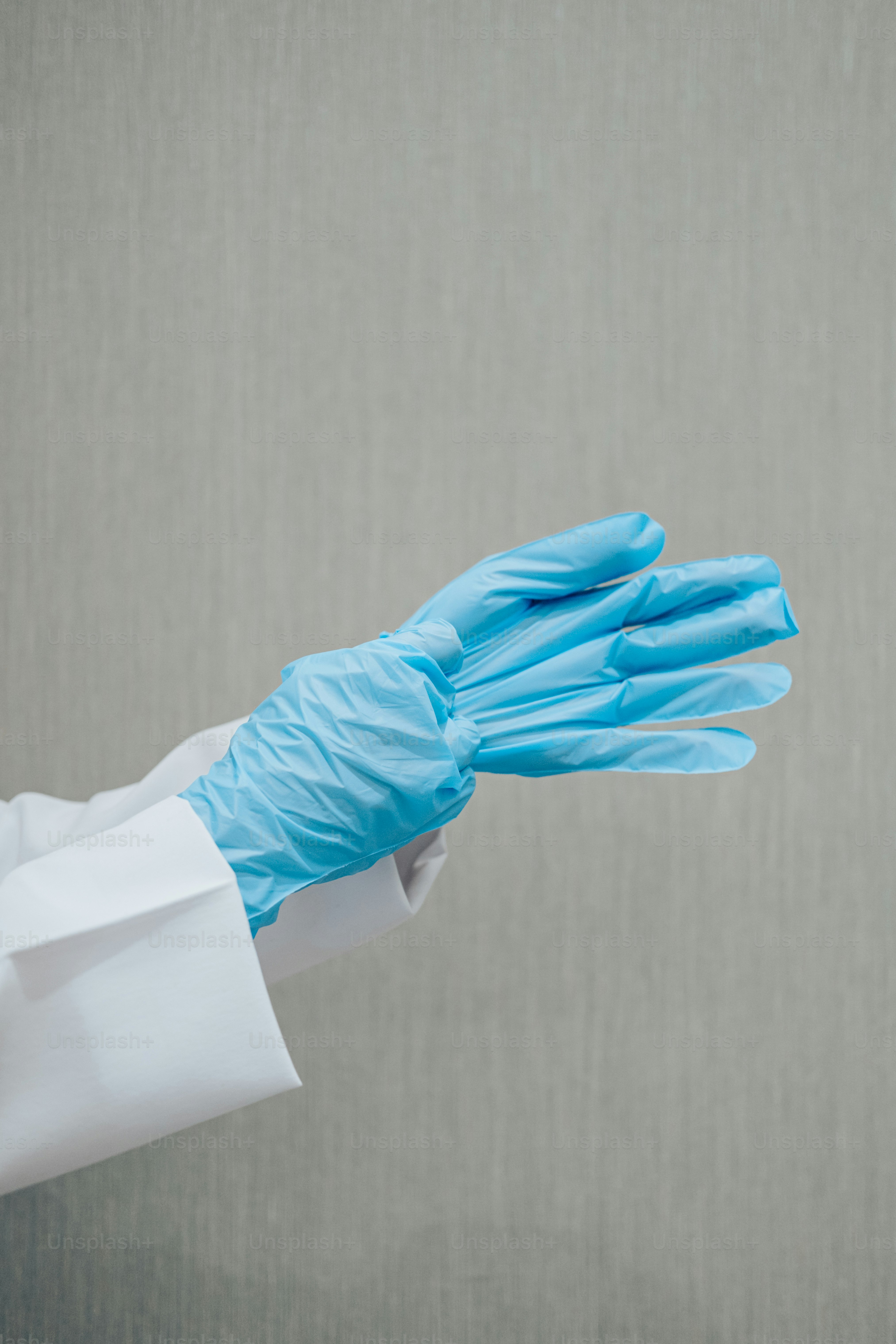 a person in a white coat and blue gloves