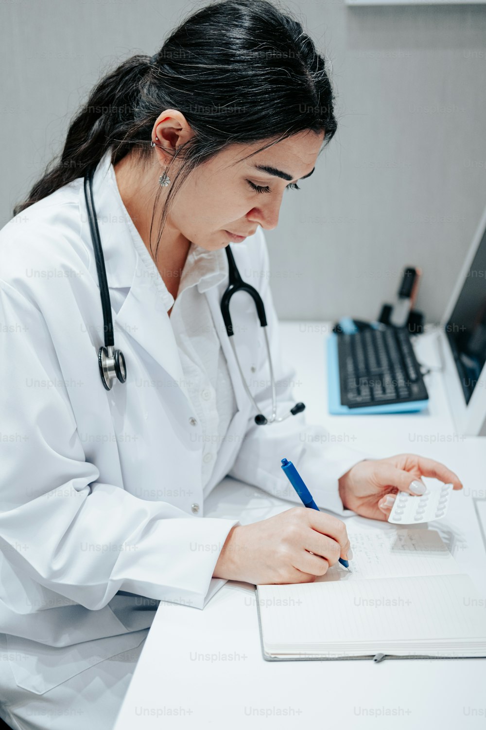 a woman in a white lab coat writing on a piece of paper