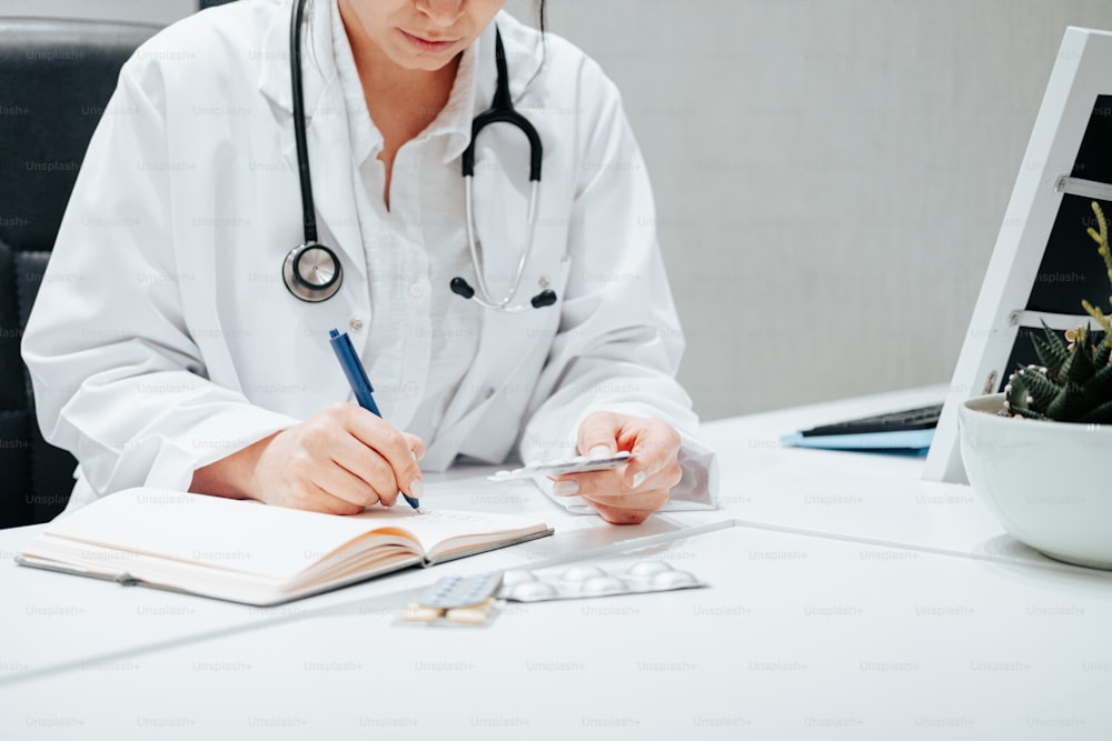 a woman in a white lab coat writing on a notebook