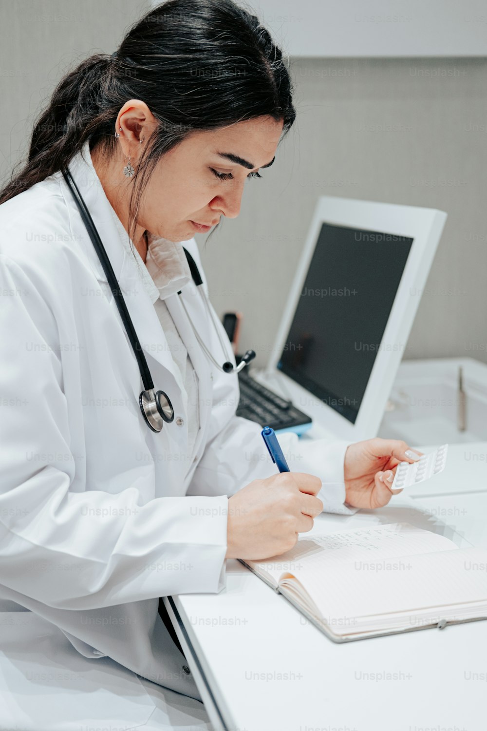 a woman in a white lab coat writing on a piece of paper