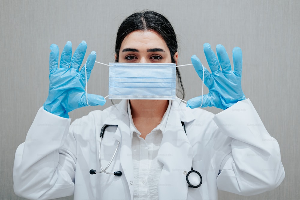 eine Ärztin mit Maske und blauen Handschuhen