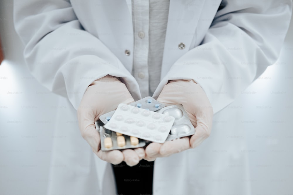 una persona in camice da laboratorio che tiene un pacchetto di pillole