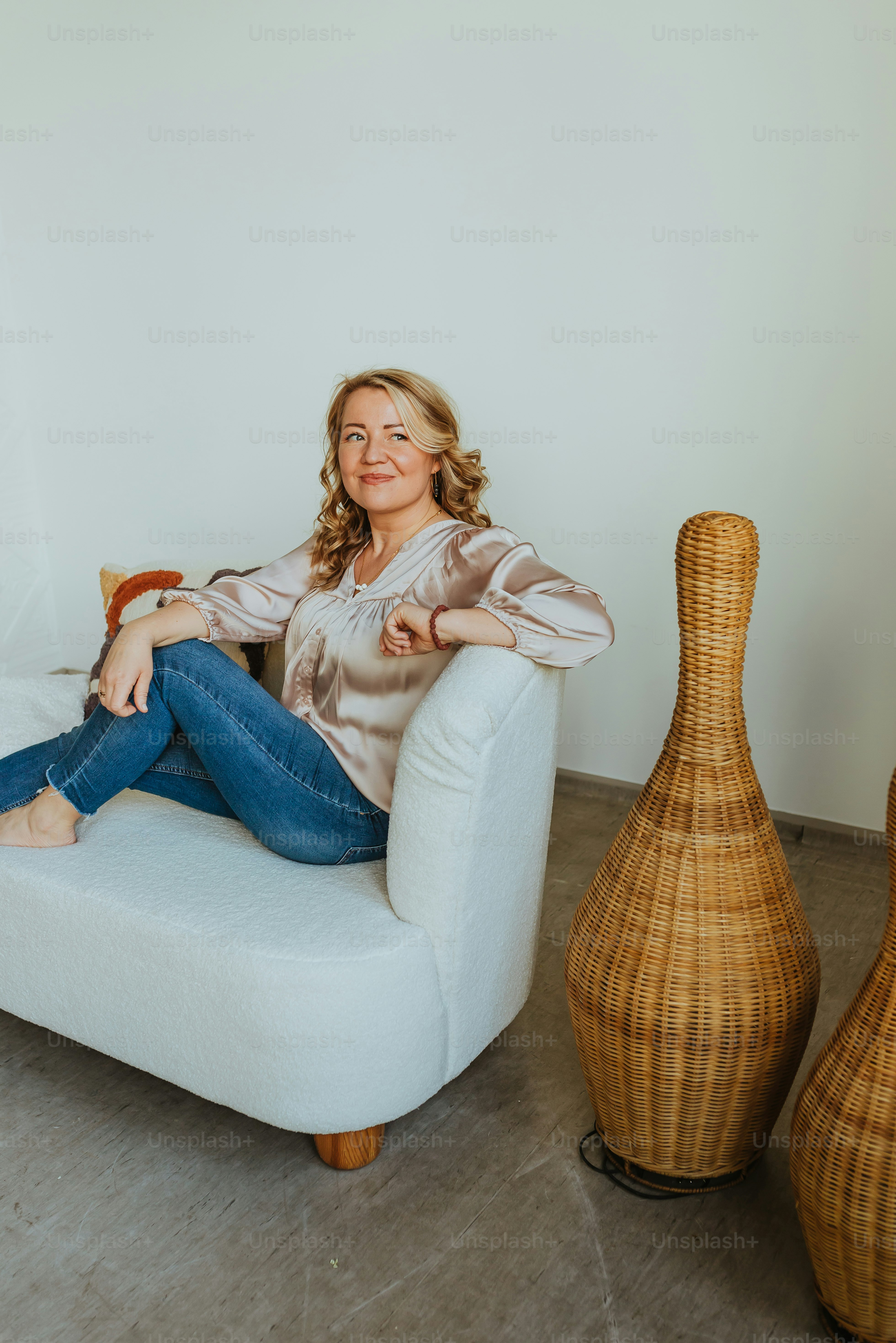 a woman sitting on a white chair next to two vases