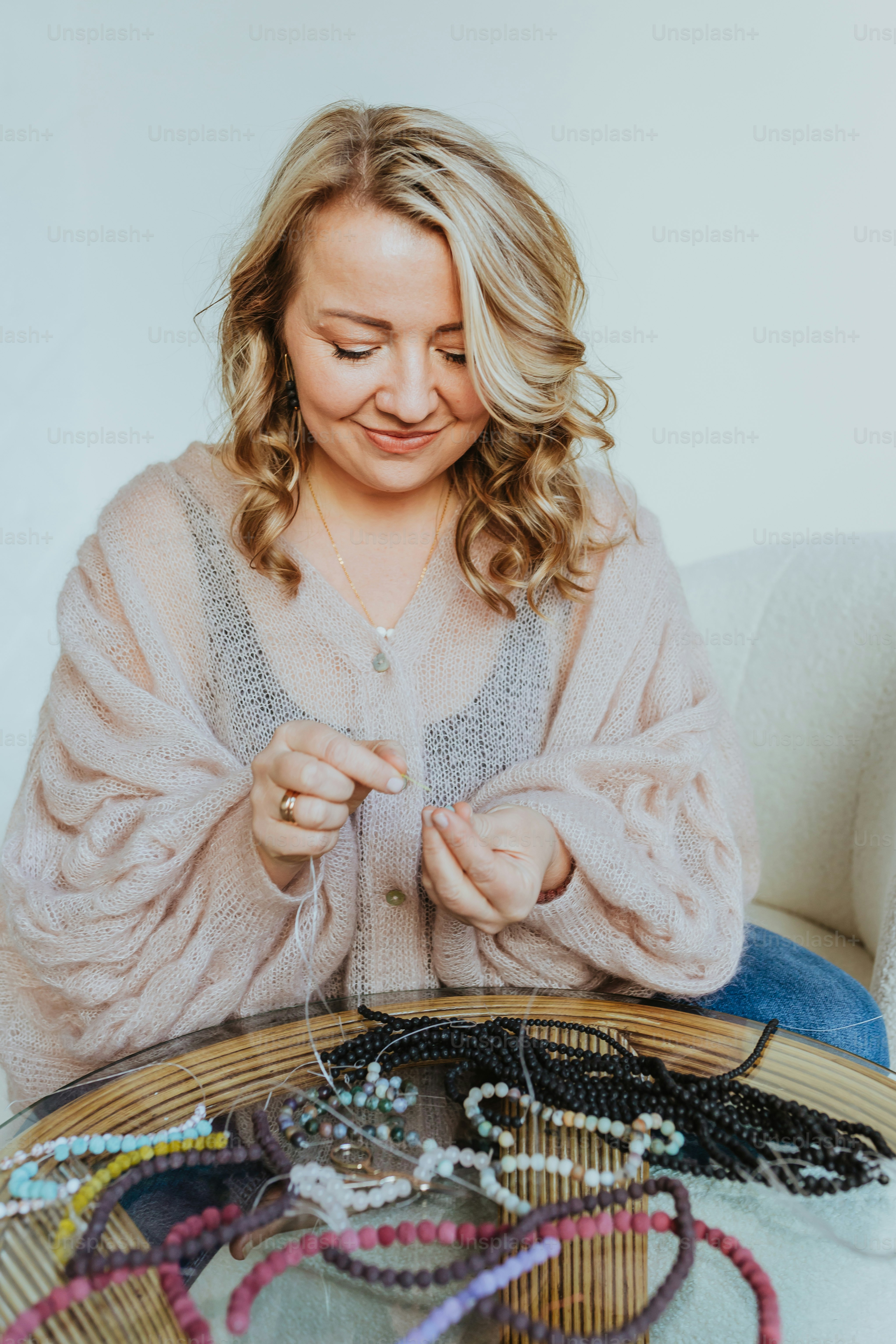 a woman sitting at a table with a bunch of beads