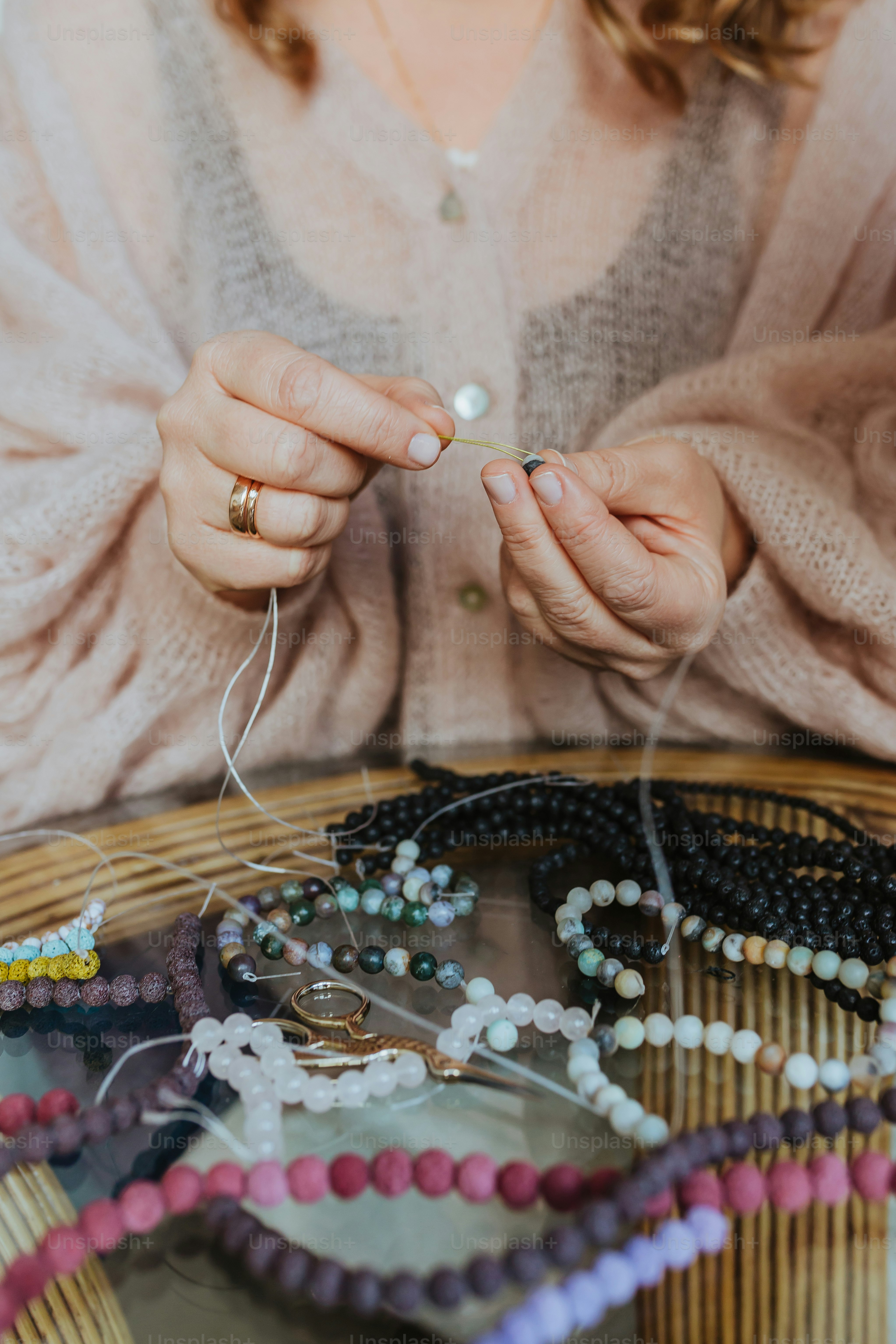 a woman sitting at a table holding a string of beads