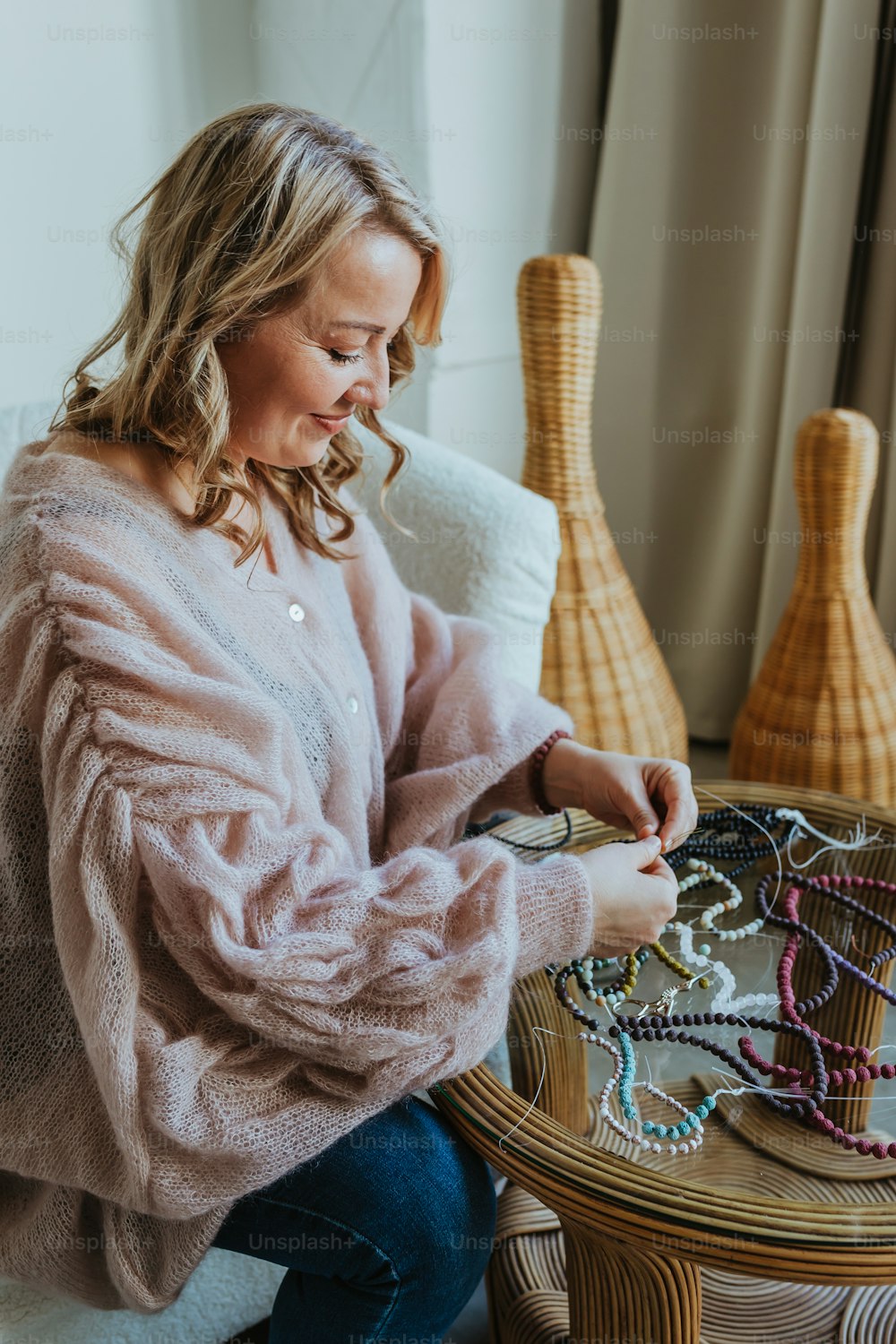 a woman sitting on a couch looking at a bunch of necklaces