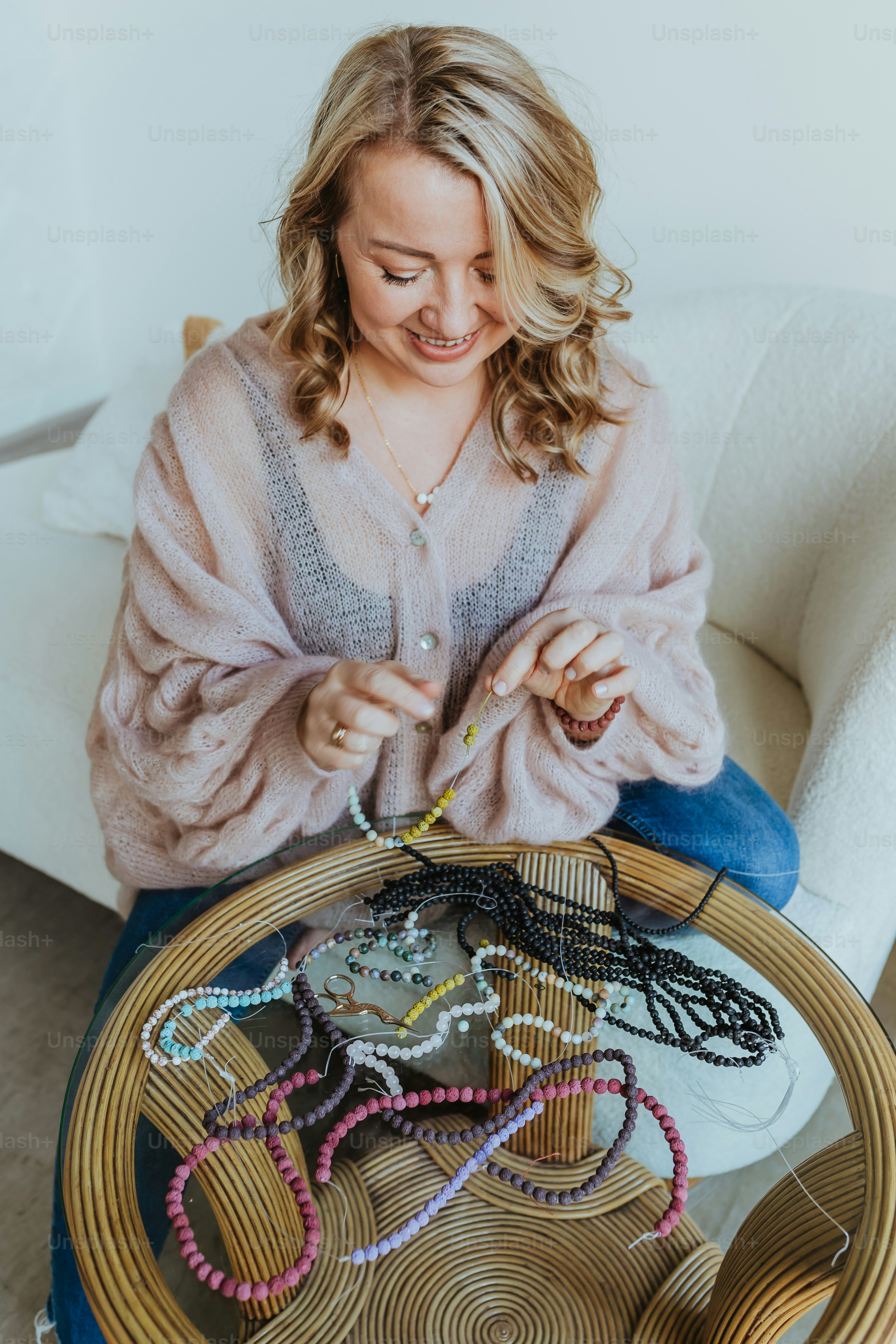 a woman sitting at a table with a bunch of beads on it