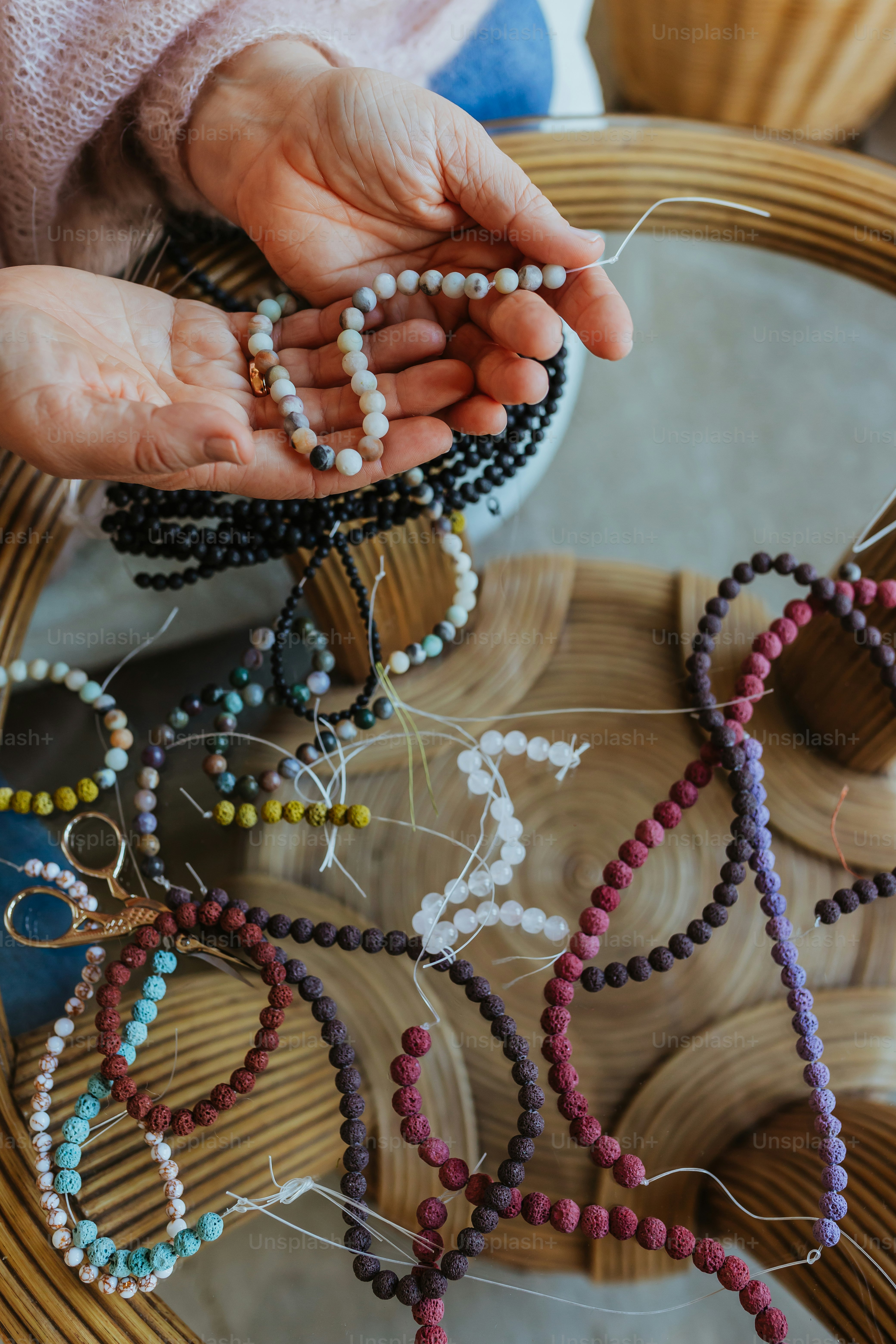 Eine Person, die Perlen in den Händen auf einem Tisch hält