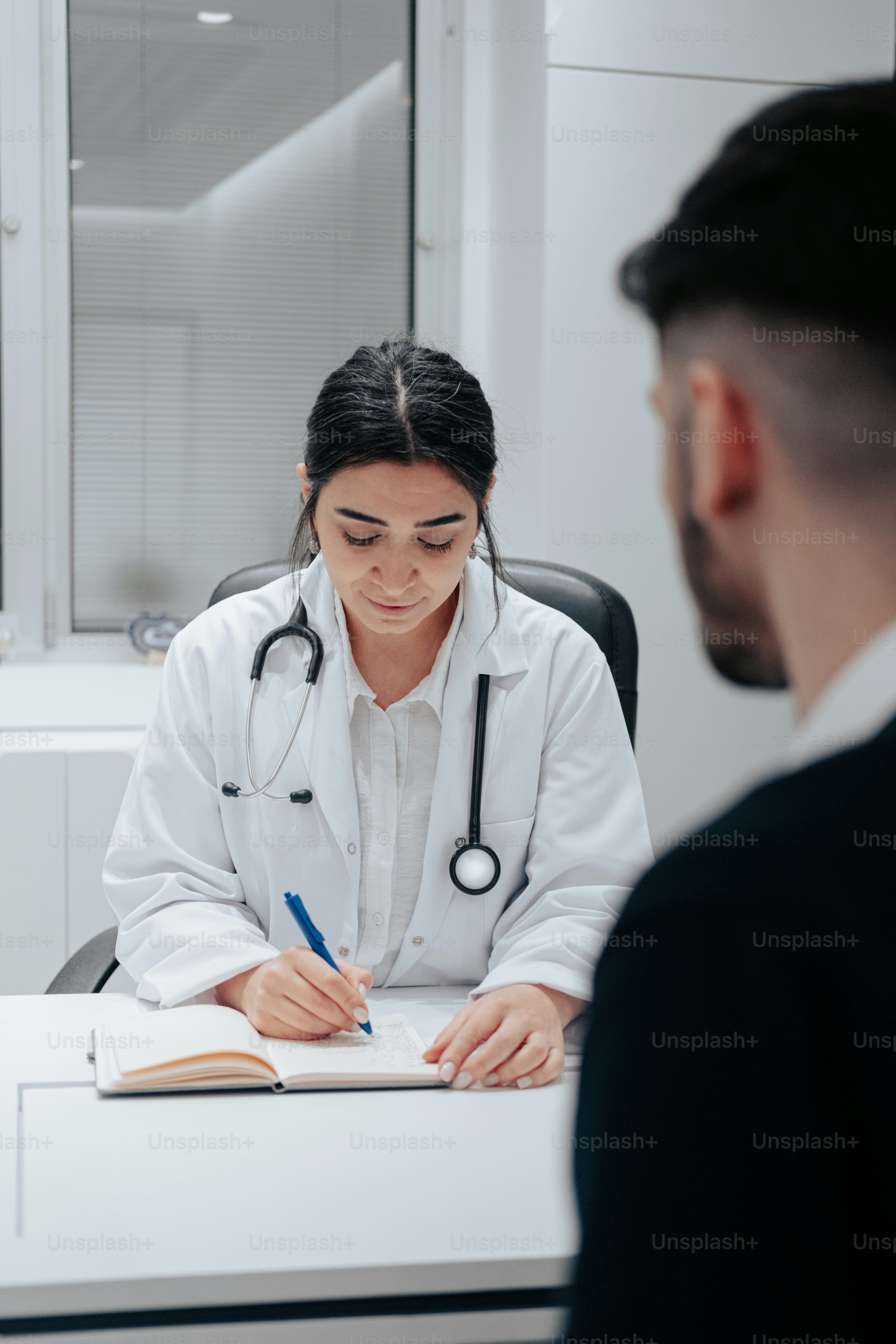 a woman in a white lab coat writing on a notebook