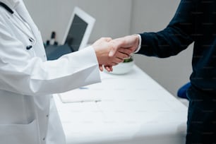 two people shaking hands in front of a desk