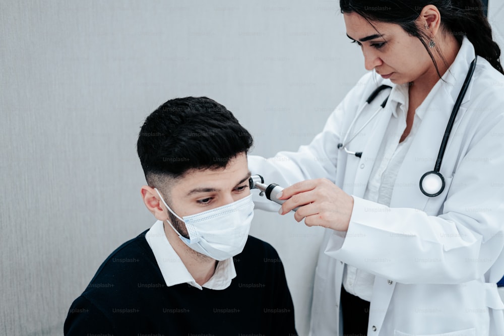 un médico que examina la cara de un hombre con un estetoscopio