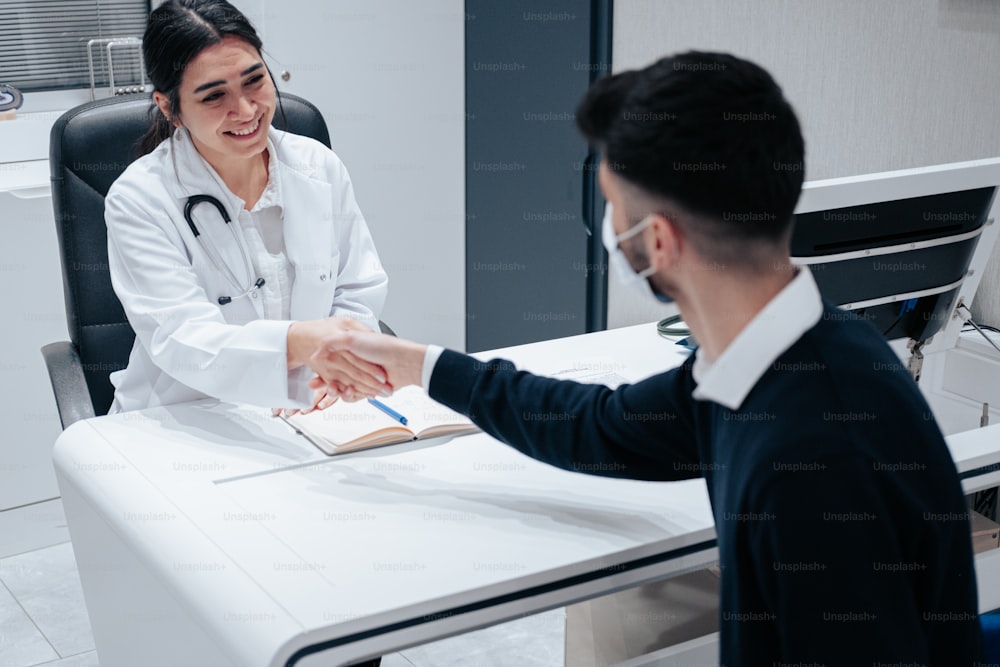 a doctor shaking hands with a patient at a desk