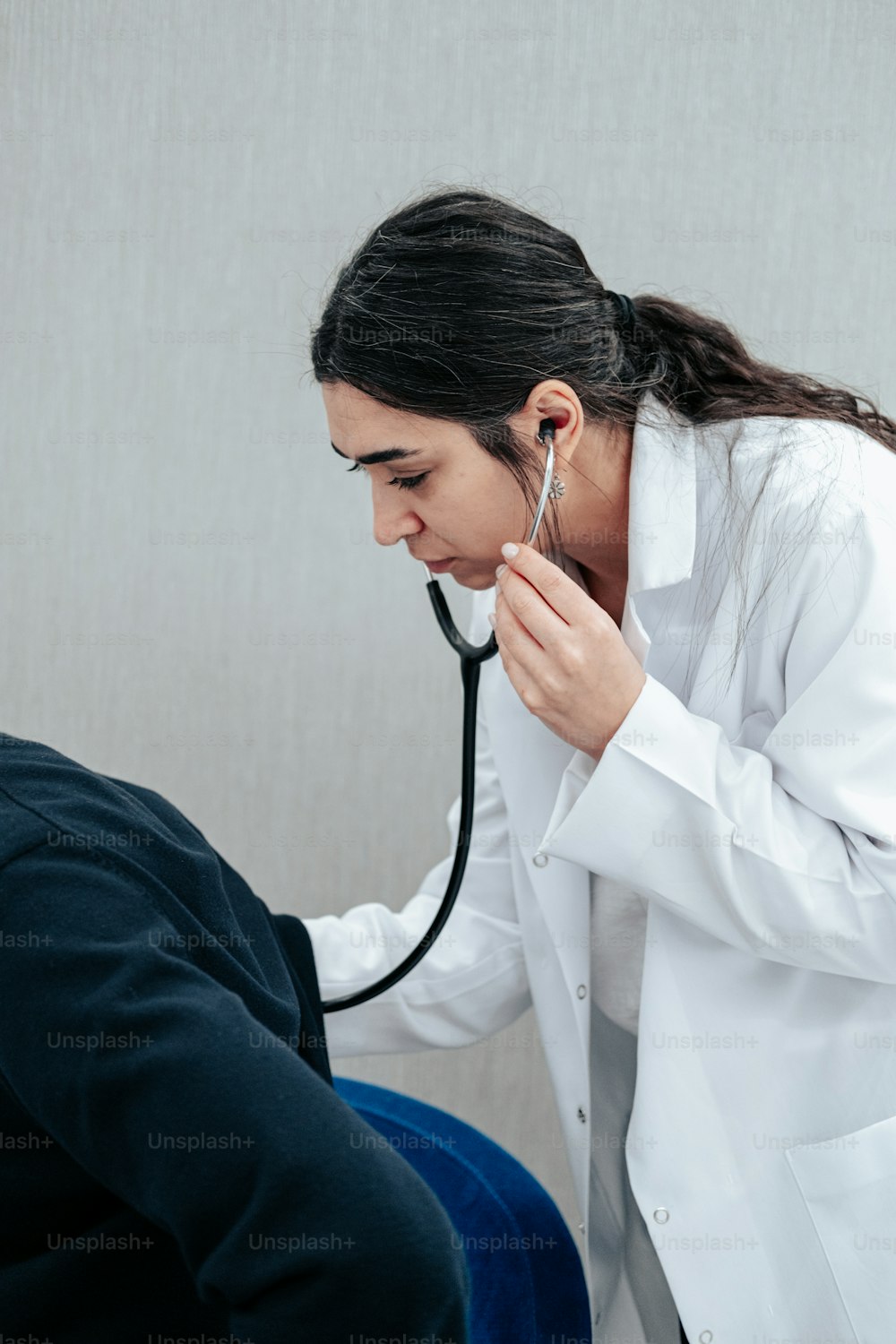 Una mujer con un estetoscopio escuchando el oído de un hombre