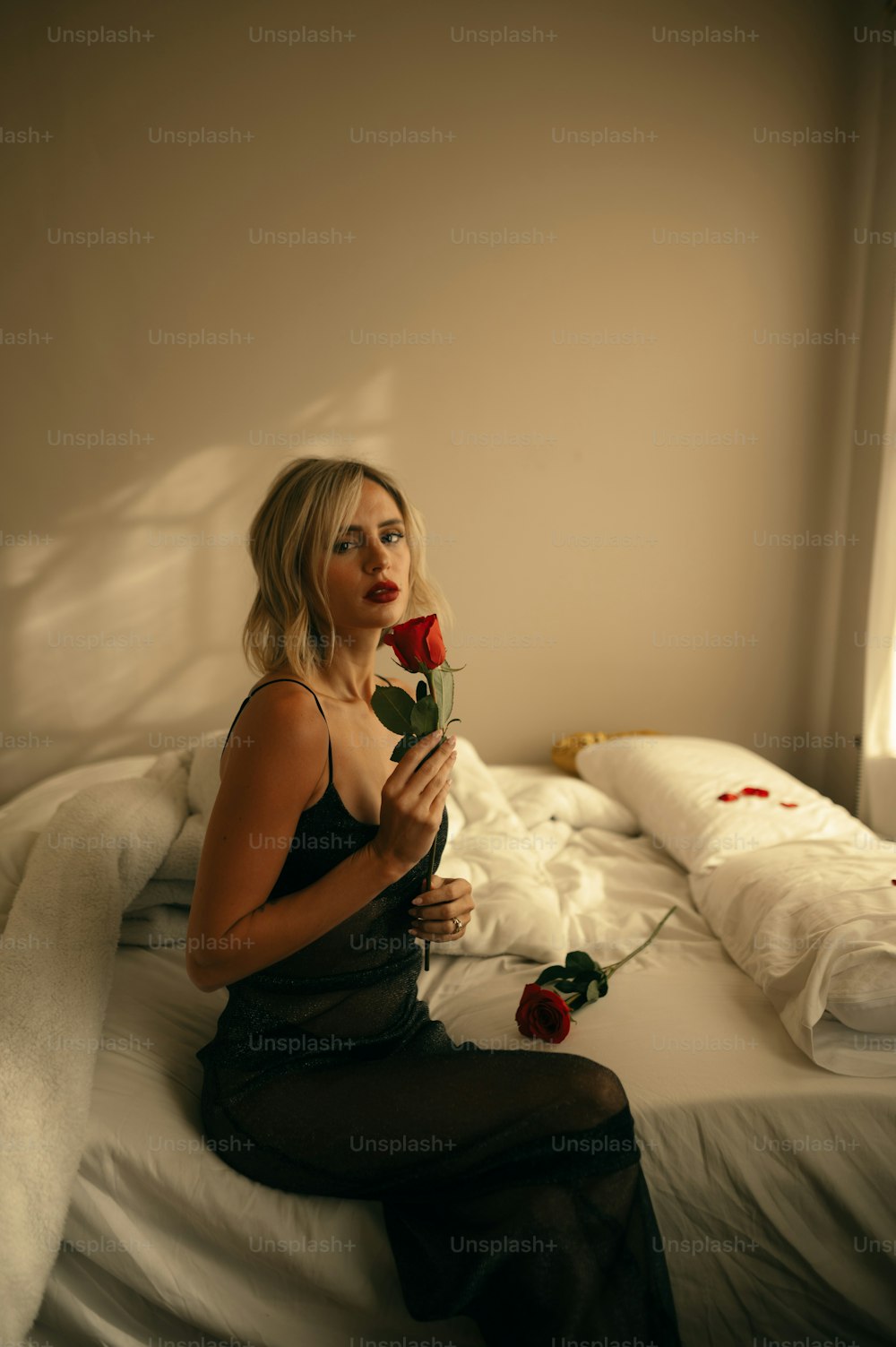 uma mulher sentada em uma cama segurando uma rosa
