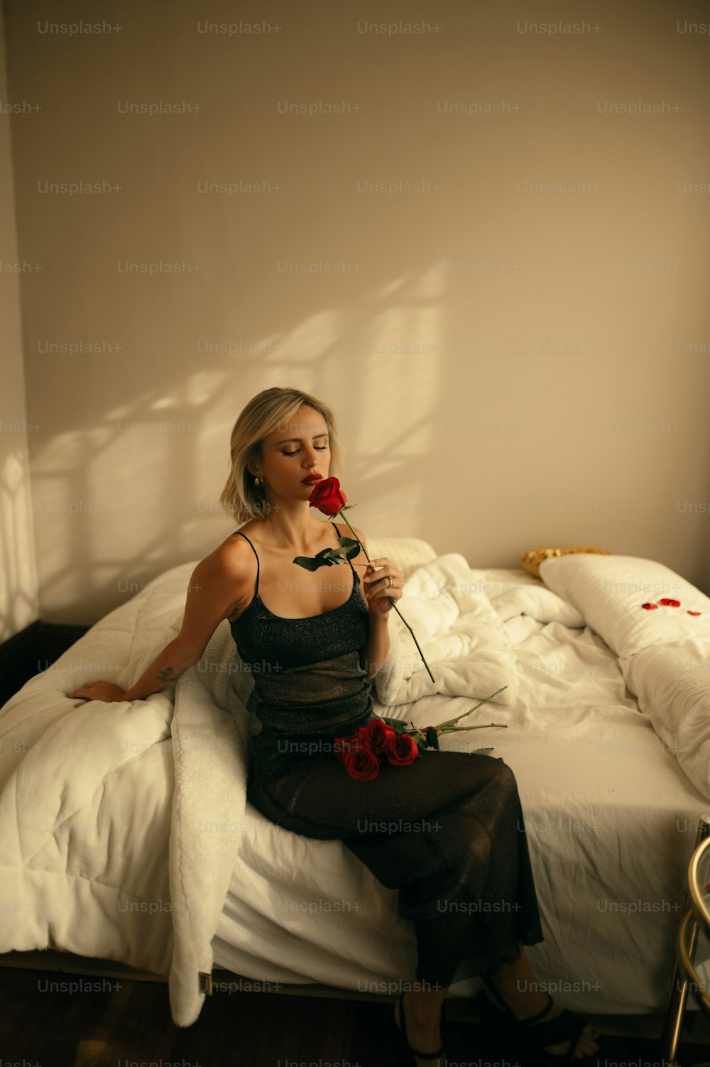 a woman sitting on a bed with a rose in her hand