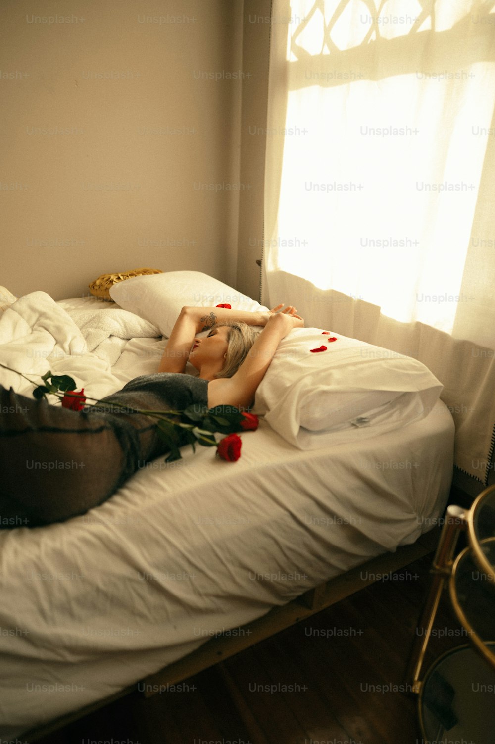 uma mulher deitada em cima de uma cama ao lado de uma janela
