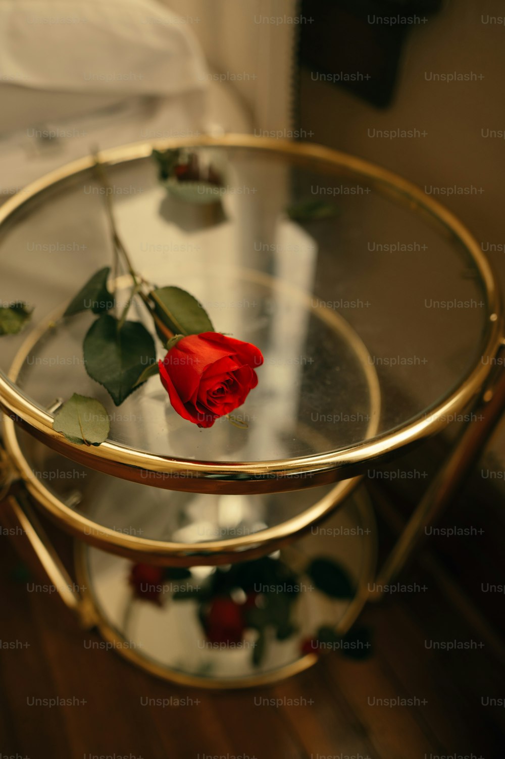 una rosa rossa seduta sopra un tavolo di vetro
