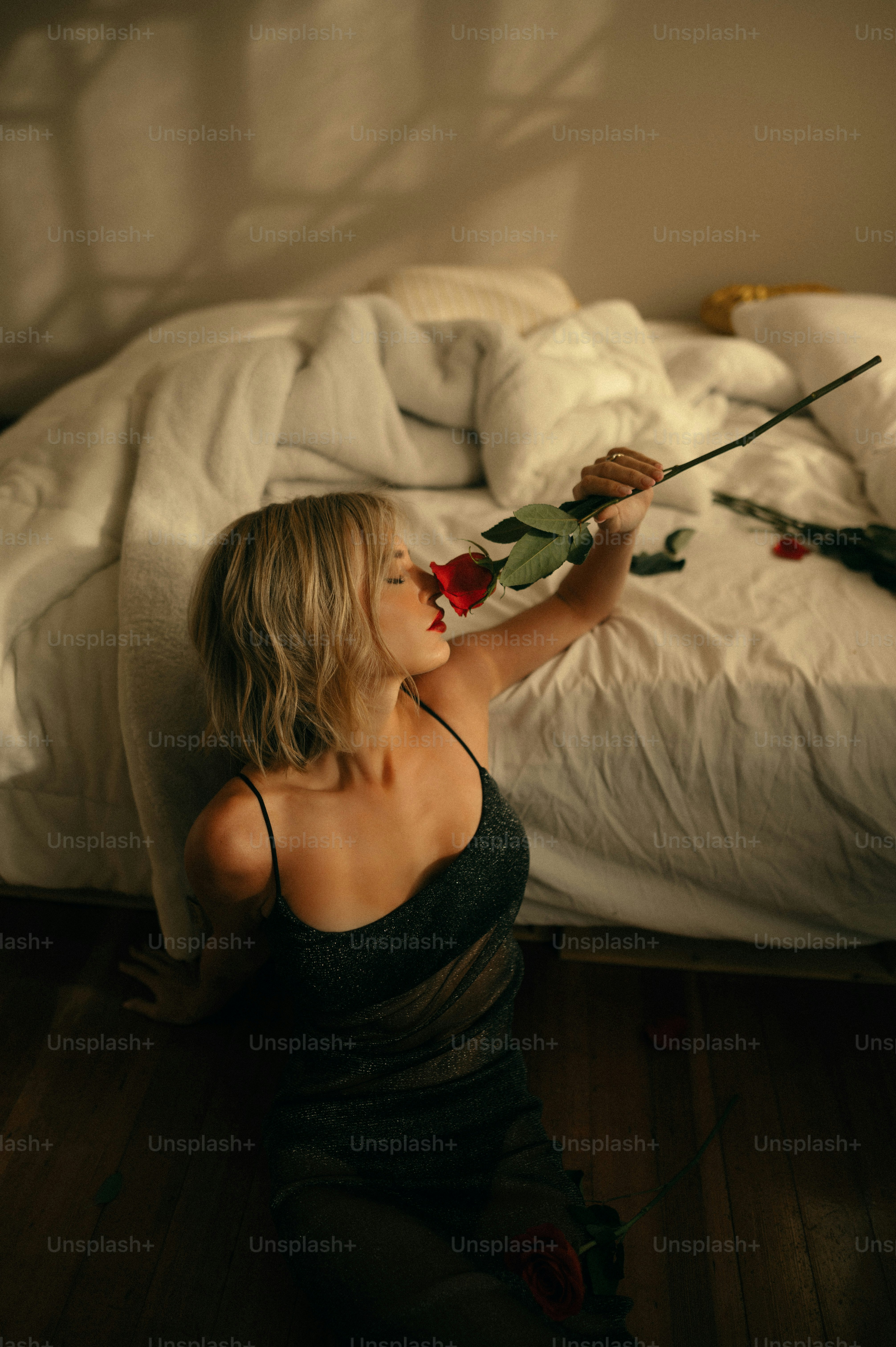 a woman sitting on a bed with a rose in her hand