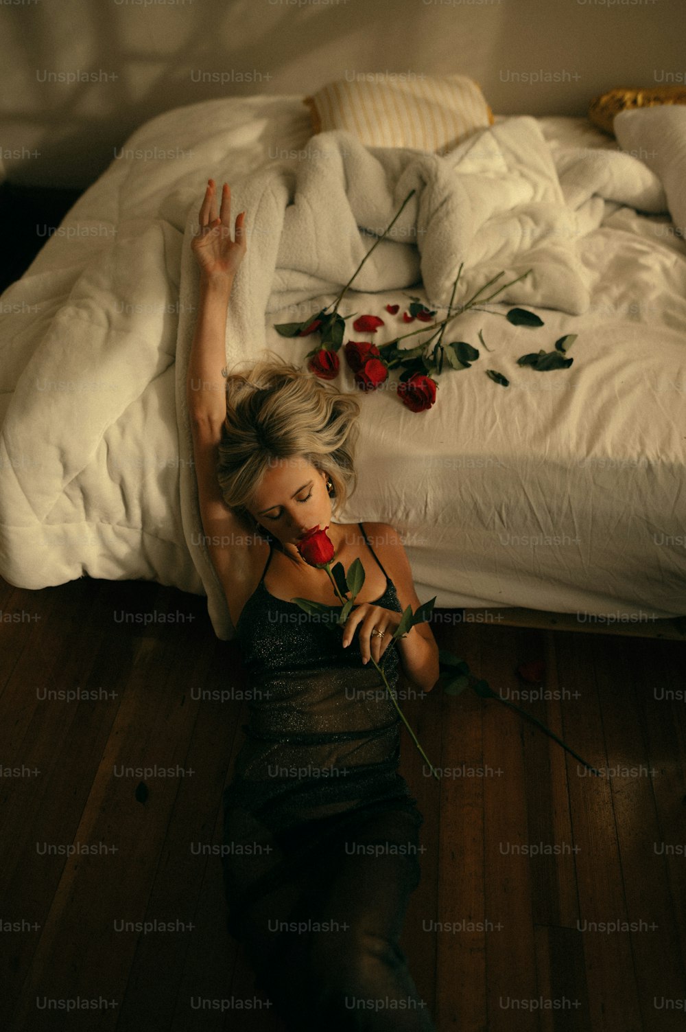 a woman laying on the floor with a rose in her hand