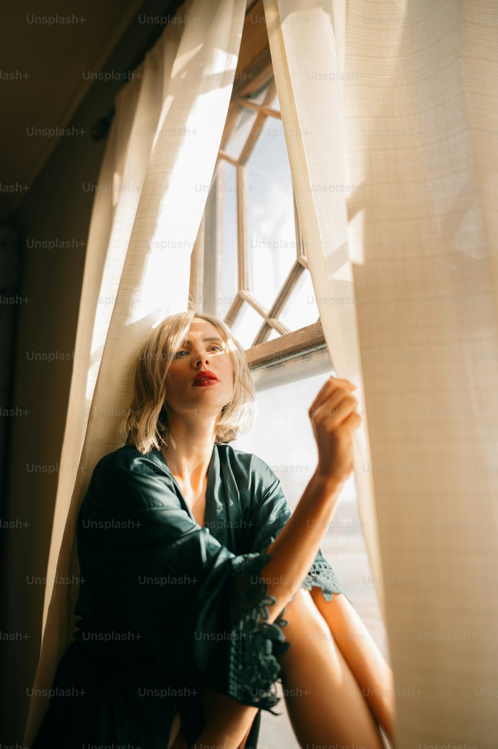Eine Frau sitzt auf einer Fensterbank und schaut aus dem Fenster