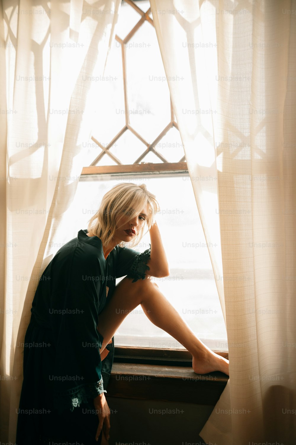 Eine Frau sitzt auf einer Fensterbank vor einem Fenster