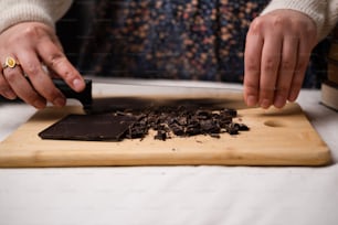 a person cutting chocolate on a cutting board
