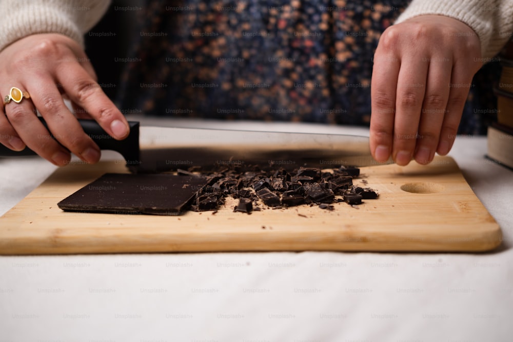 une personne coupant du chocolat sur une planche à découper
