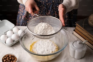 uma pessoa misturando ingredientes em uma tigela em uma mesa