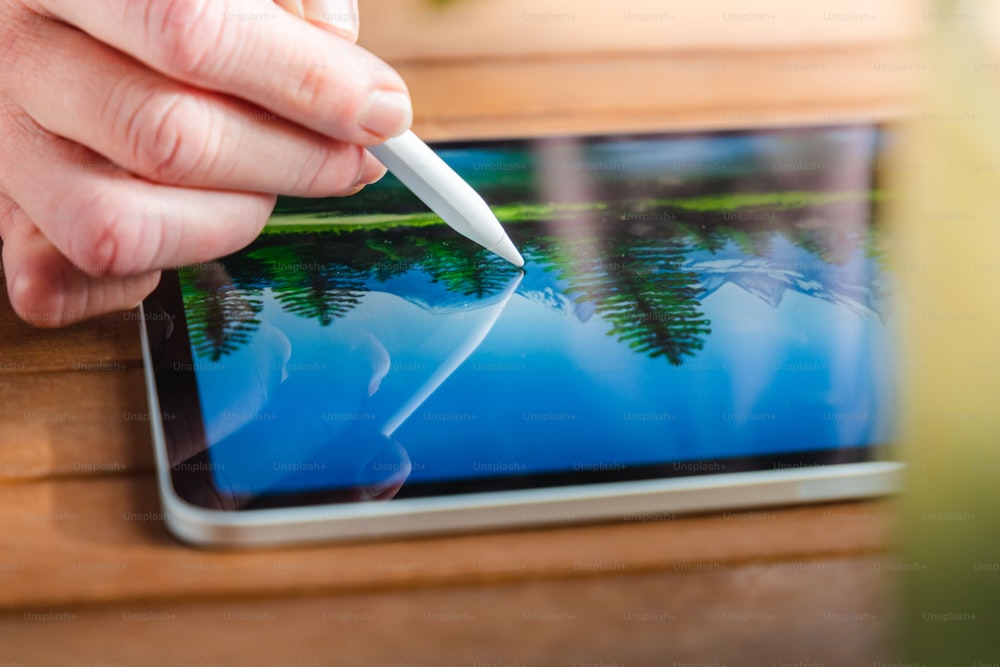 a person is holding a pen over a tablet