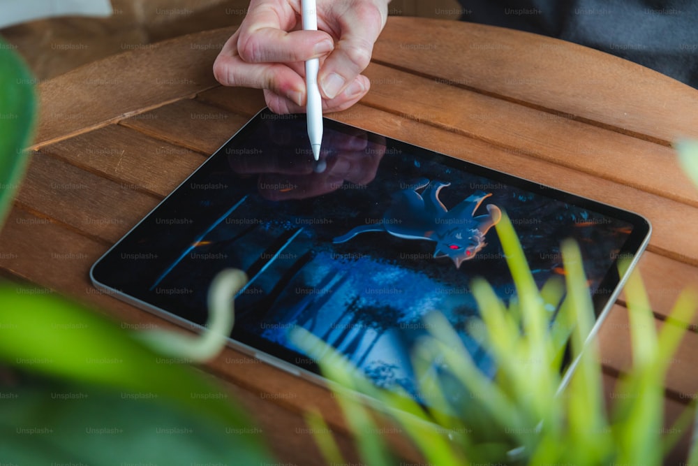 a person holding a pen and writing on a tablet