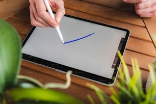펜으로 태블릿에 글을 쓰는 사람